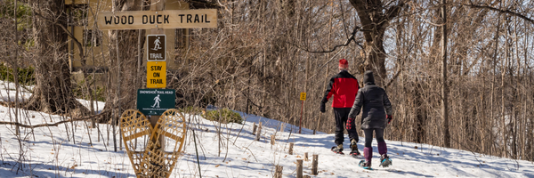 2 people snowshoeing past the sign